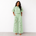 Conjunto elegante de mujer de dos piezas de invitada de boda con calado floral y pantalón fluido